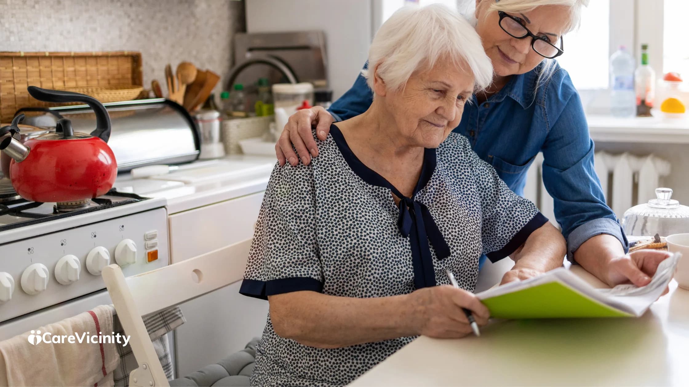 An older woman and a younger woman reviewing paperwork together at a home kitchen table