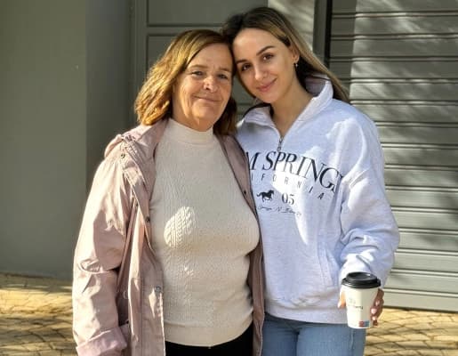 Two women standing together outdoors and smiling at the camera