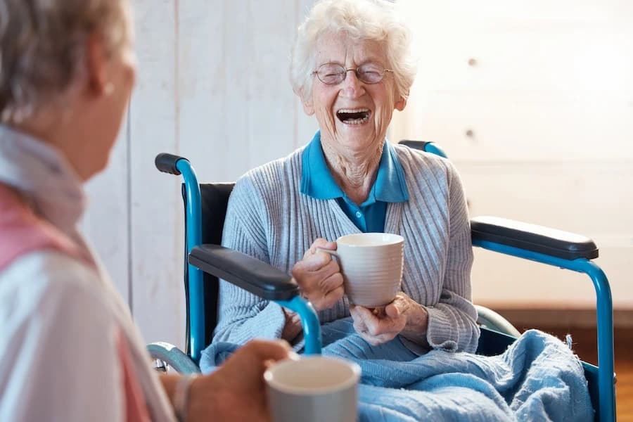 Older woman in wheelchair enjoying companionship during in-home aged care visit