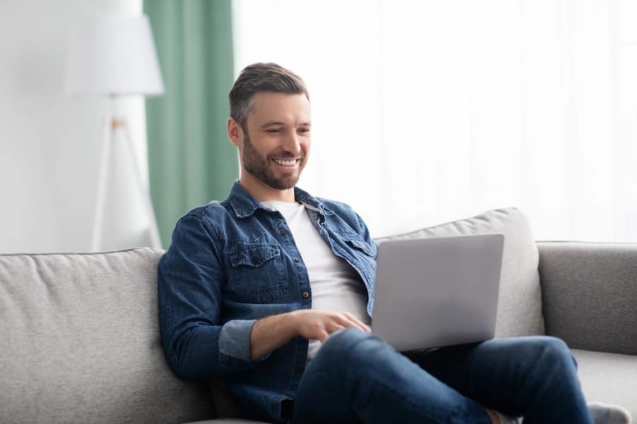 Man sitting on a couch using a laptop at home