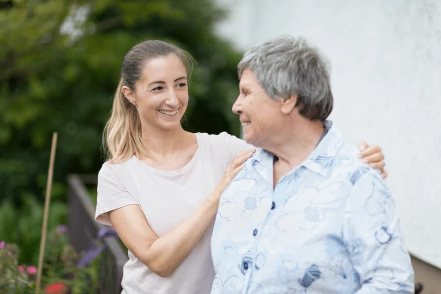 Younger woman standing with an older woman outdoors
