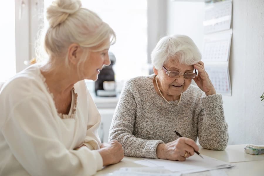 Two older women sitting at a table reviewing papers together