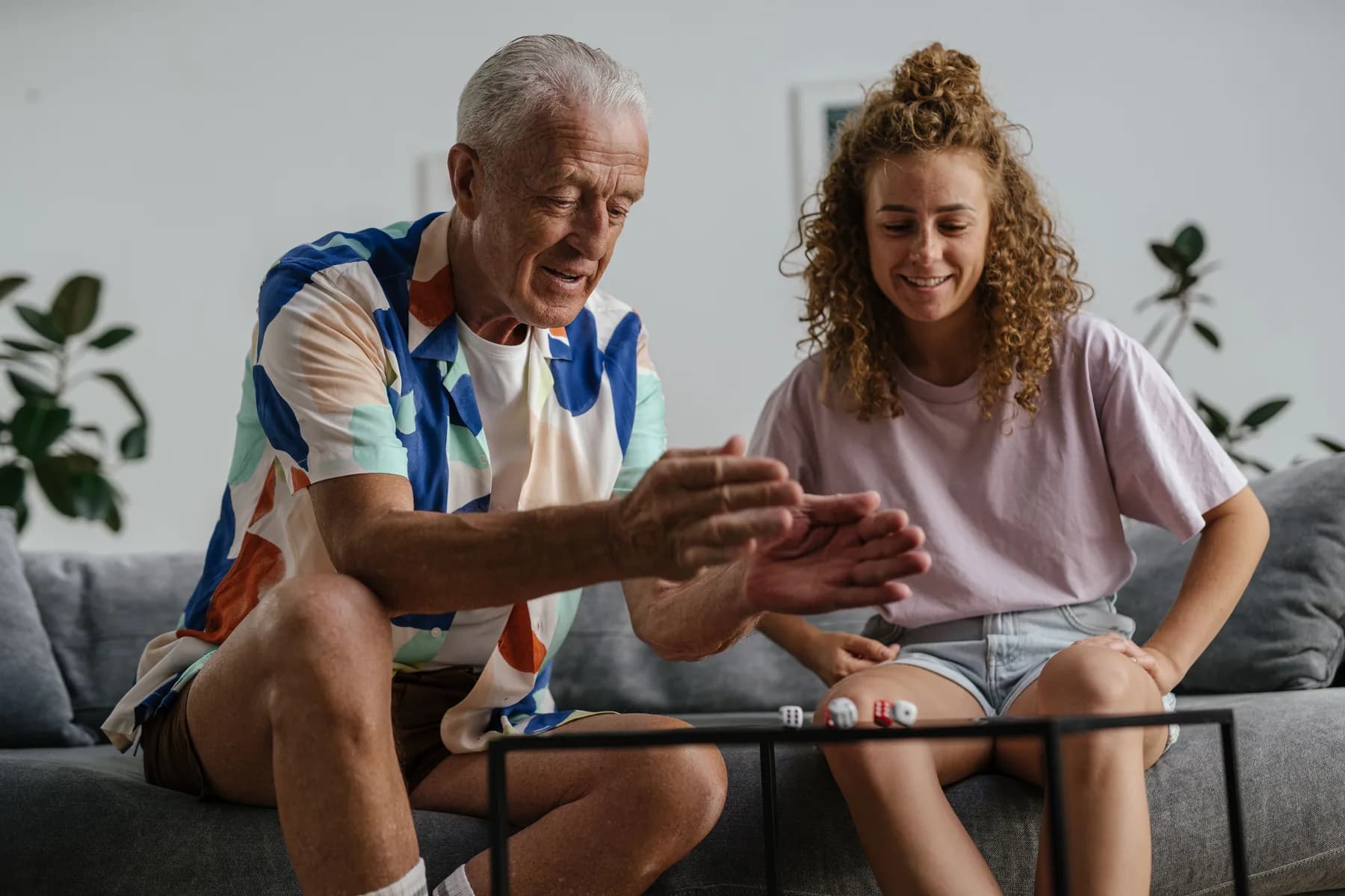 Older man and a younger woman playing a board game together on the couch