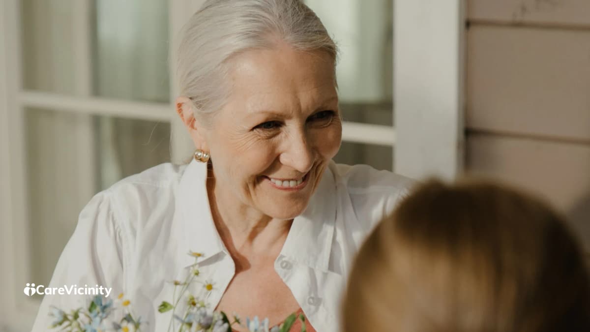 An older woman smiling warmly, in conversation, soft natural light