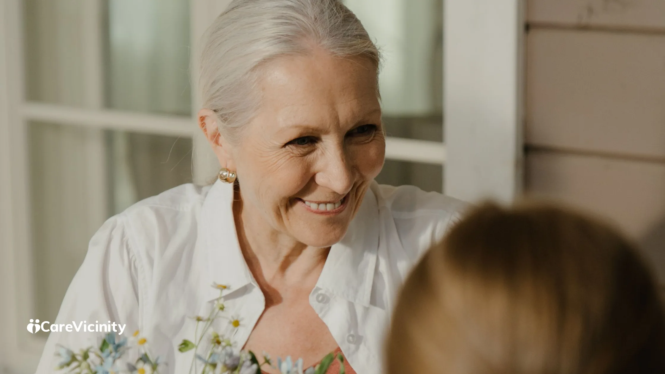 An older woman smiling warmly, in conversation, soft natural light