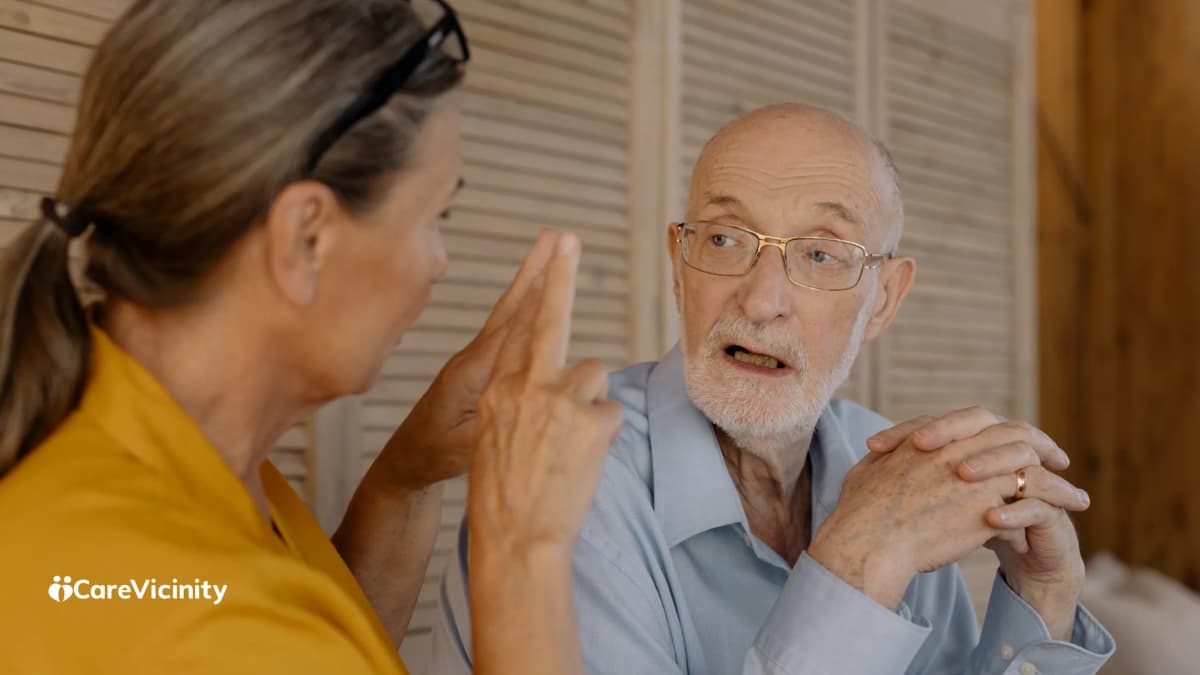 Older man in conversation with a woman at home, discussing something together