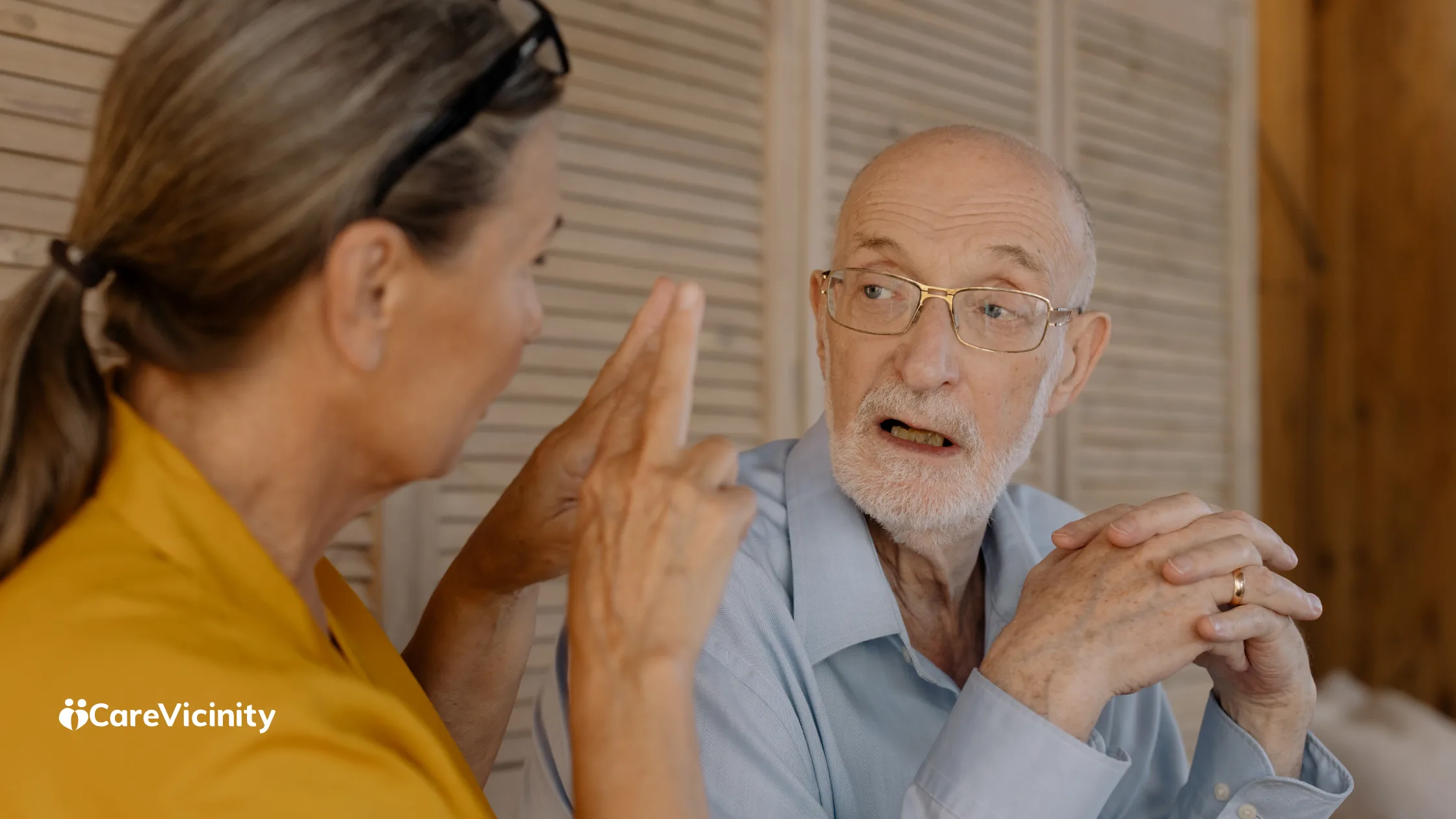Older man in conversation with a woman at home, discussing something together