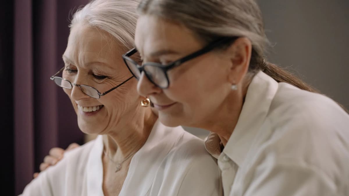An older woman and a visitor chatting over a cup of tea at a kitchen table