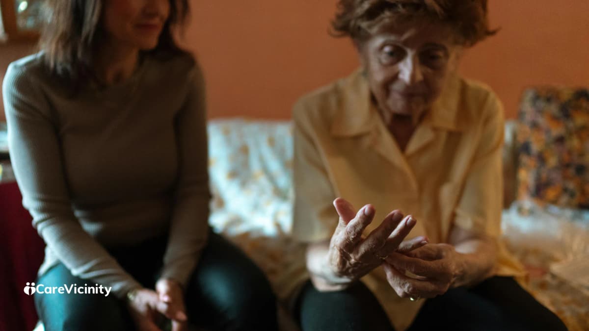 An older woman and a younger family member sitting together at home, talking through a care decision.