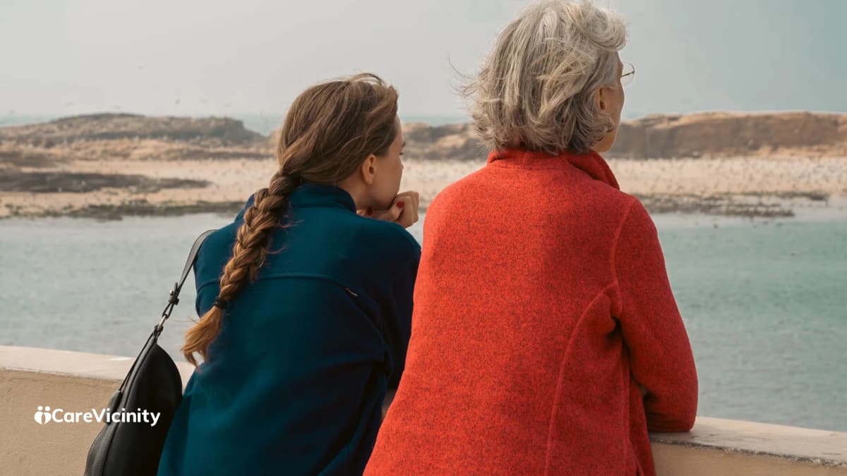 Two women standing together looking out over water, deep in conversation.