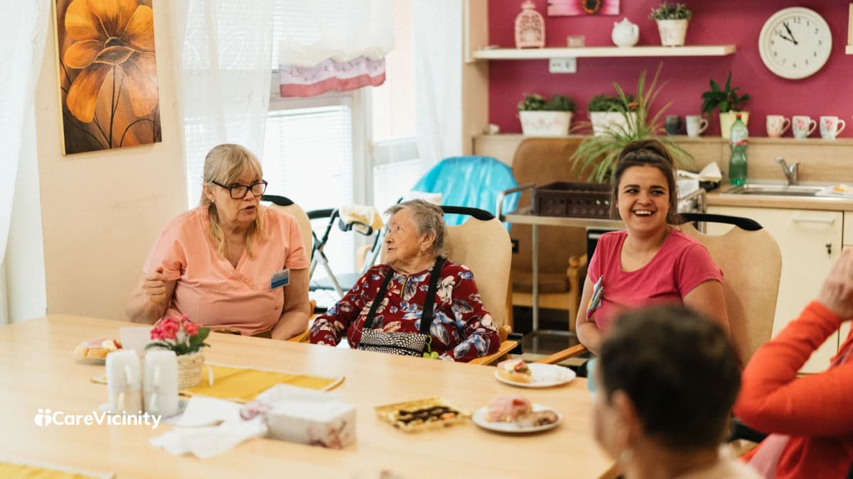 A support worker and an older client sharing a warm conversation, seated together indoors