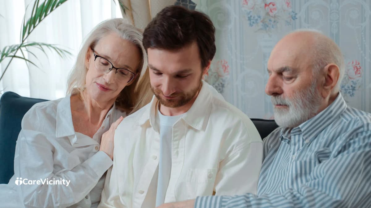 An older couple sitting with their adult son on a couch, looking over paperwork together