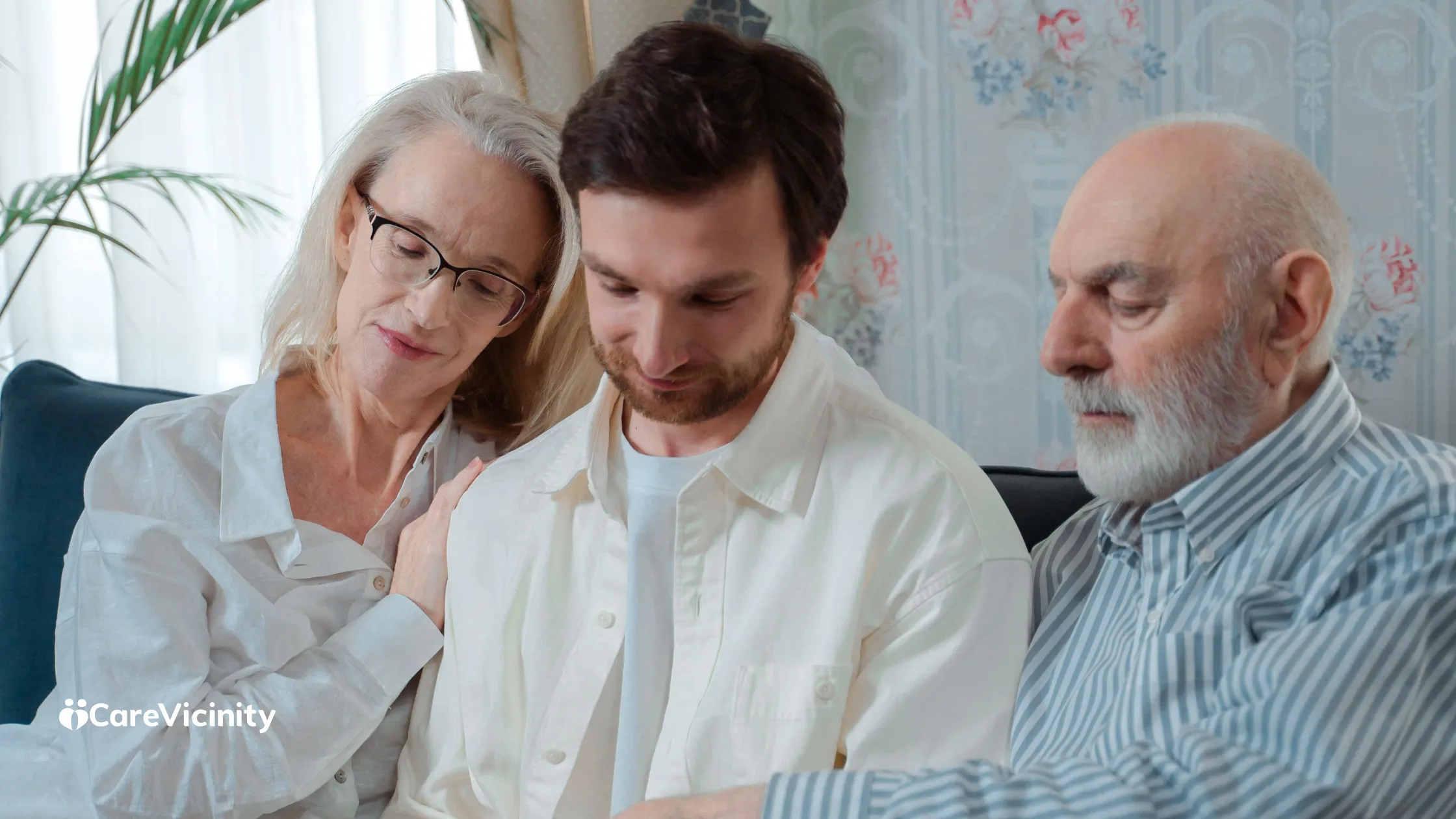 An older couple sitting with their adult son on a couch, looking over paperwork together